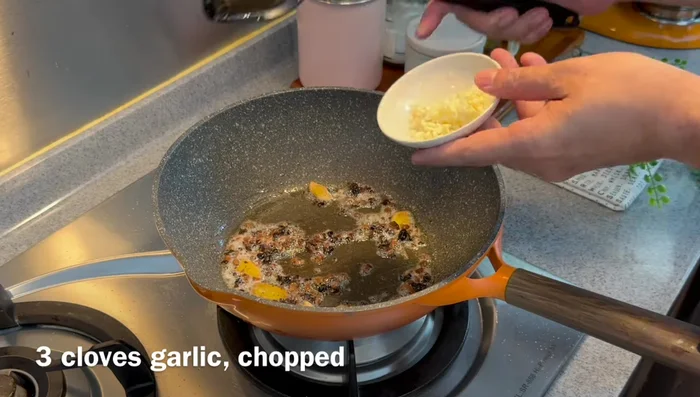 Add chopped garlic and the white parts of the spring onions, fry until fragrant.