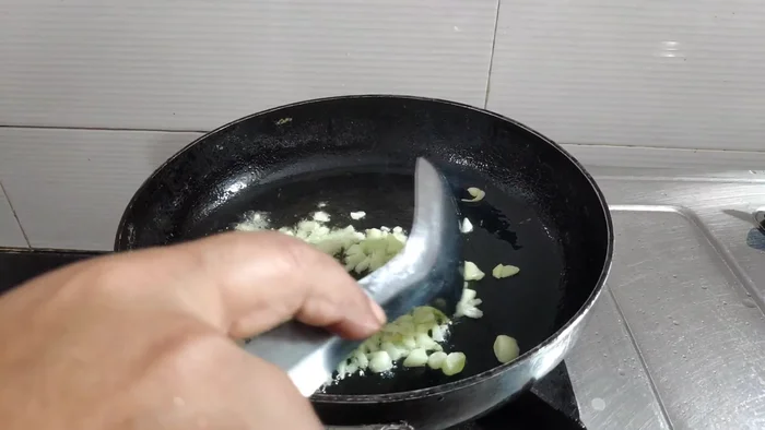 Heat oil in a wok or frying pan until it starts to smoke. Add garlic, ginger, and green chilies and stir-fry for a few seconds.
