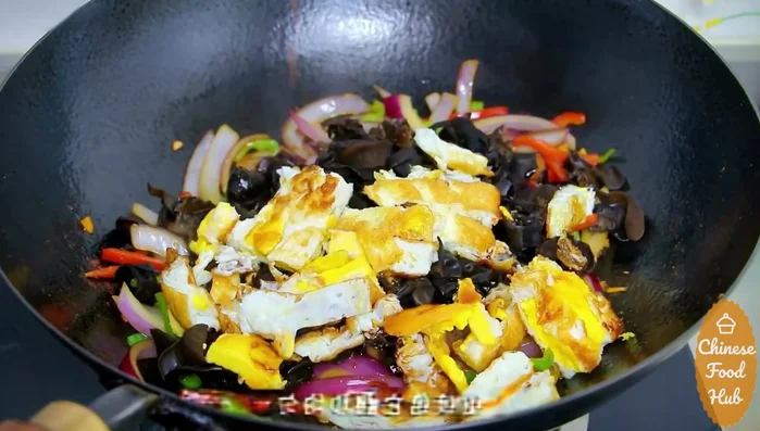 Add the blanched wood ear mushrooms and cooked egg strips. Pour in the prepared sauce and stir-fry to combine.