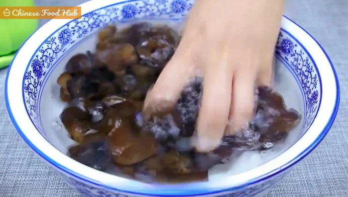 Squeeze out excess water from the wood ear mushrooms, remove tough parts, and slice into strips.