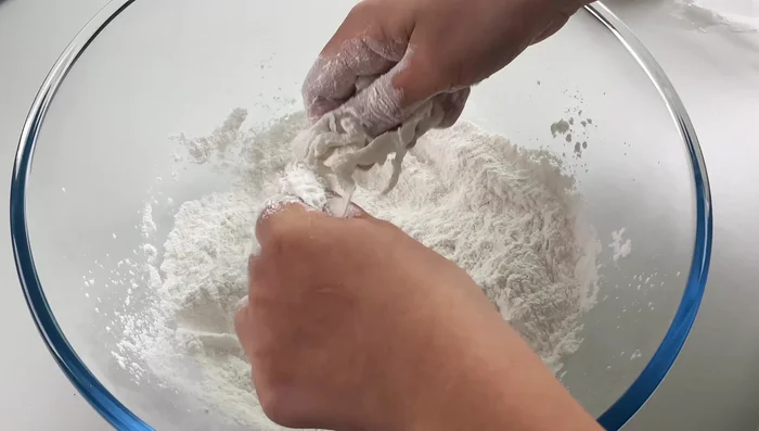 Gradually add water, mixing until a smooth dough forms. (This step likely involves kneading the dough)