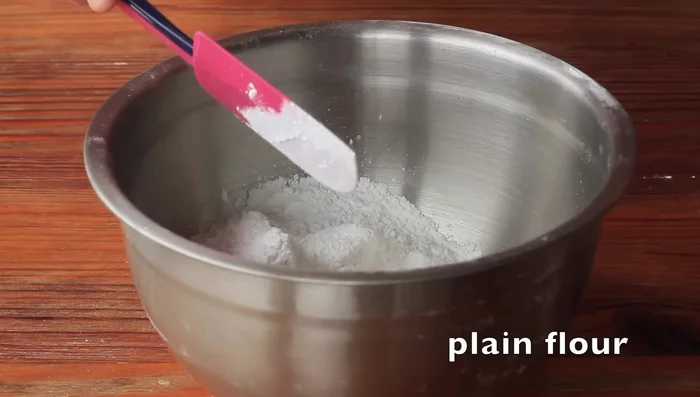 Gradually add water while mixing until a smooth batter is formed. The consistency should be similar to pancake batter. (Note: Specific water quantity is not provided in the audio transcript)