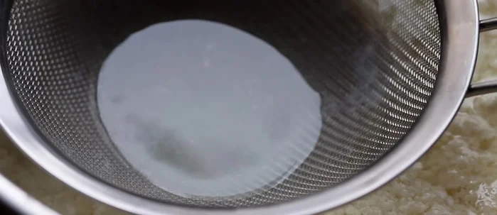 Carefully transfer the curds (tofu) to a presser to remove excess water.