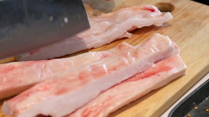 Begin the process of rendering pork lard. (This step likely involves cutting the pork fat into smaller pieces.)