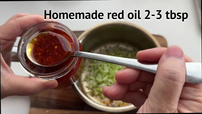 In the same pan, add minced ginger and green onion. Add 2-3 spoonfuls of chili oil. Heat until sizzling, then remove from heat.
