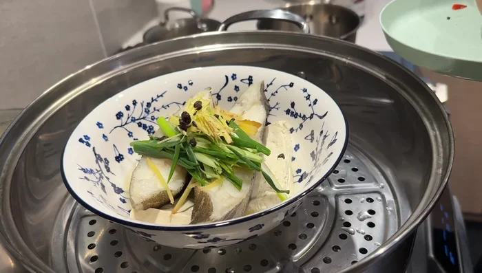 Top the steamed fish with ginger, scallions, fermented black beans (if using), and chili peppers (if using).