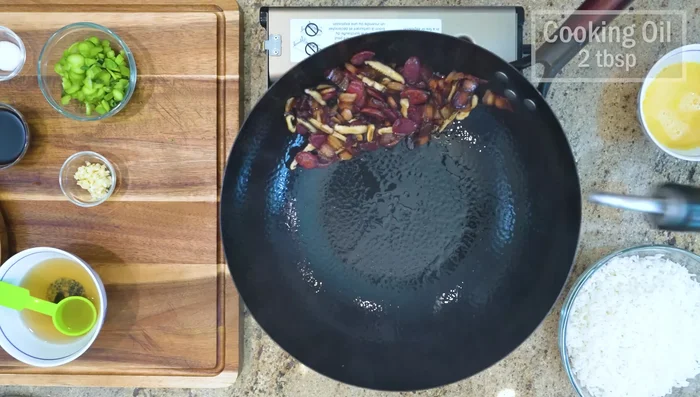 Turn the heat to high, push the ingredients to the side, and add oil to the wok. Pour in the eggs and scramble quickly.