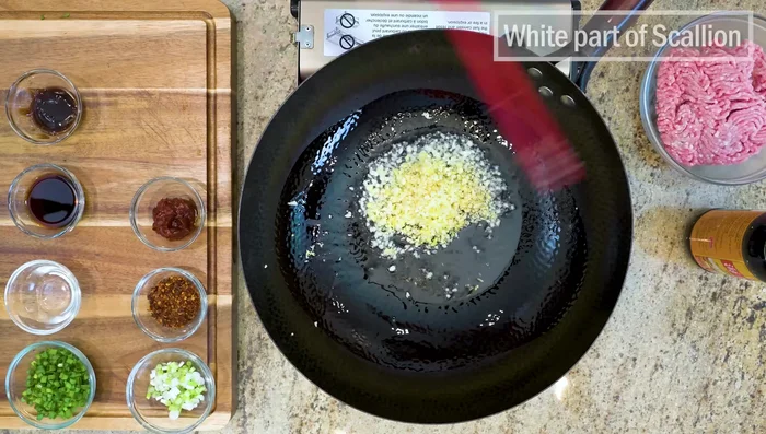 Heat oil in a wok, add garlic-ginger blend, white scallions, Sichuan Doubanjiang, and chili flakes (or substitutes). Stir for a couple of minutes.