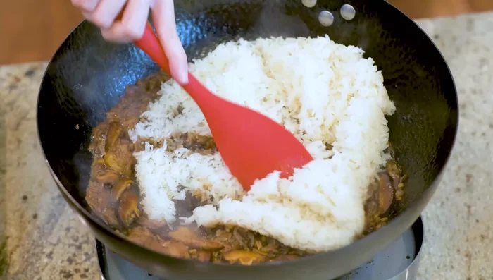 Add the steamed glutinous rice to the wok and mix until no white rice remains. Turn off heat when sauce is absorbed to prevent sticking.