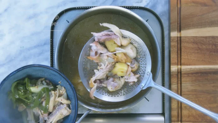 Strain the chicken broth to remove solids, then strain again through an oil strainer to remove excess oil.