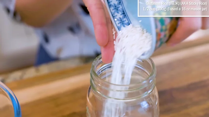 Add half cup of gluten rice into a mason jar. Rinse it with clean water a few times and drain completely.