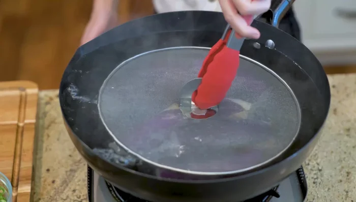 Add eggplants to boiling water, using a utensil to keep them submerged.