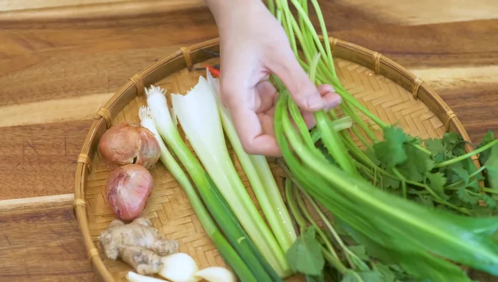 Finely dice garlic, ginger, shallot, scallion, celery, Thai chilies, mint, cilantro, and coriander.