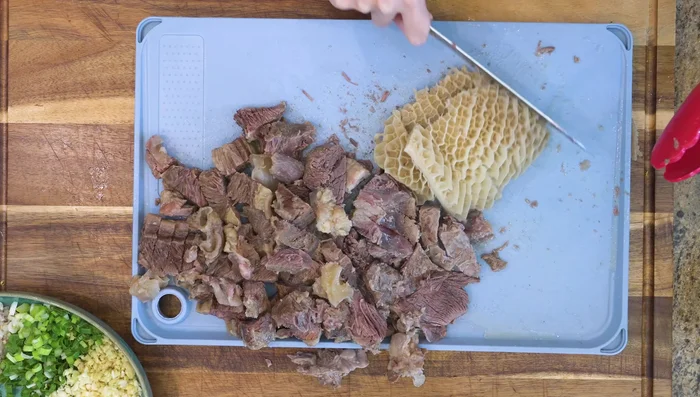 Return the beef to the clay pot. Bring to a boil again. Add the diced aromatics, salt, and Sichuan peppercorn powder.