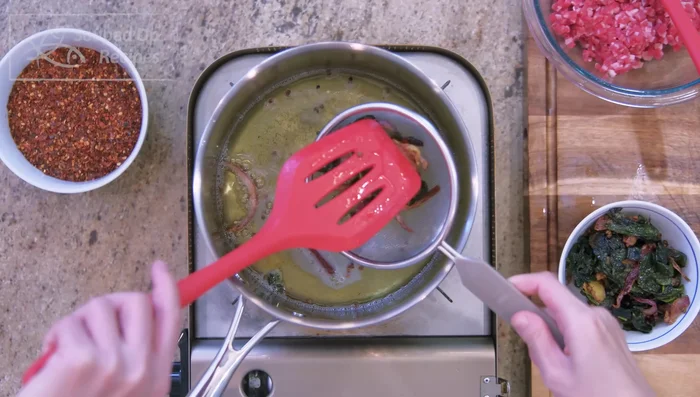 Strain out the aromatics. (Optional) Add lethospermum root to the hot oil for 20-30 seconds.