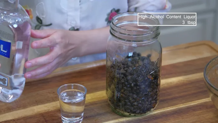 Pack the beans into a mason jar. Add liquor to a shot glass and place it in the center of the beans; seal the jar with cheesecloth, not airtight.