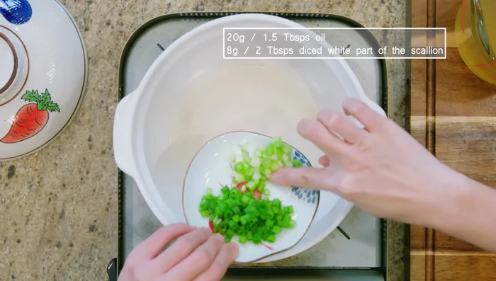 Preheat a clay pot or stock pot. Add oil, white parts of scallions, minced garlic, and minced ginger. Stir over medium heat for 2-3 minutes.