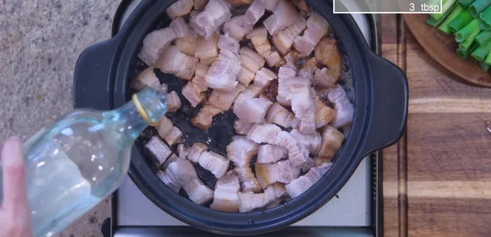 Add pork and aromatics: Add blanched pork, cooking wine, ginger, and scallions to the pot. Stir to deglaze.