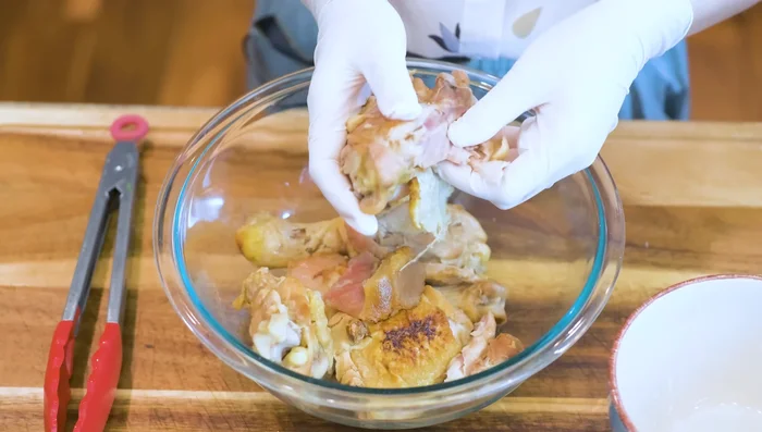 Shred chicken meat from bones; discard skin. Season shredded chicken with soy sauce, oyster sauce, fish sauce, garlic powder, and sesame oil.