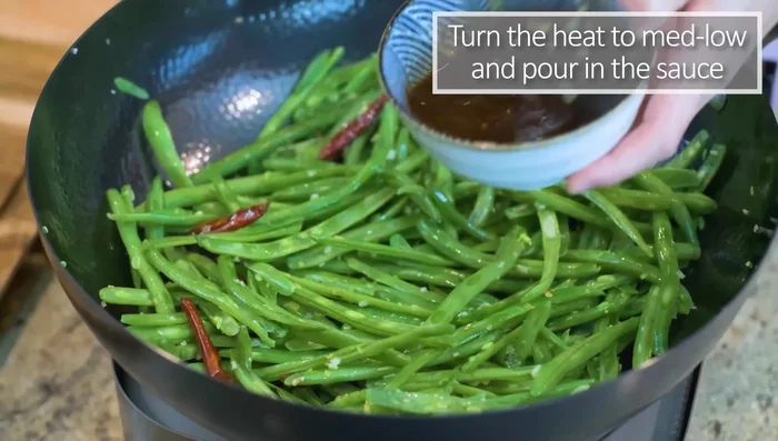 Reduce heat to medium-low. Pour in the sauce and cook for a few minutes, allowing the seasoning to infuse into the green beans until soft and pliable.