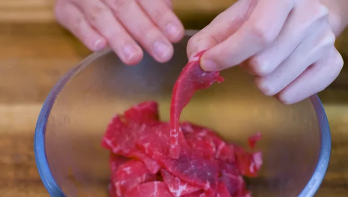 Marinate the beef (200g) with soy sauce, dark soy sauce, five spice powder, baking soda, and vegetable oil for 15 minutes.