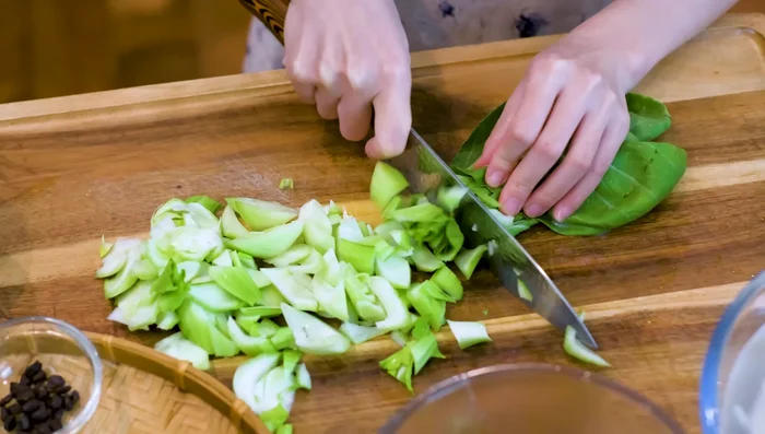 Prepare the vegetables: chop baby bok choy, slice pickled mustard green, julienne carrot, and mince garlic.