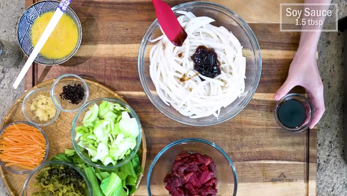 Season the drained noodles with oyster sauce, soy sauce, and white pepper.