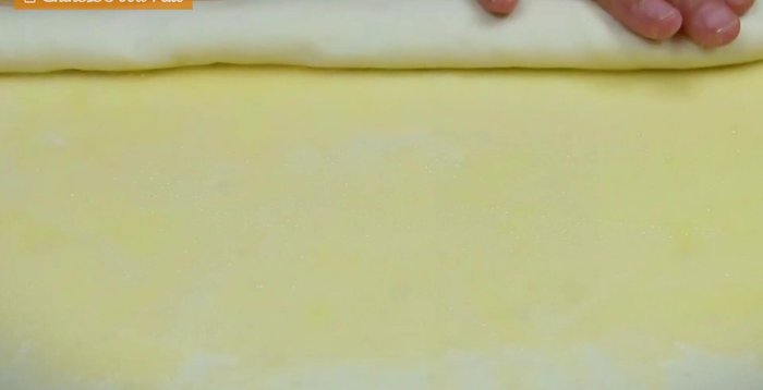 Spread the oil paste evenly on the dough, fold it like a dumpling, and pinch to seal. Fold in half again, gathering the sides towards the center to form a round shape. Flatten and roll out again, making the edges thinner.