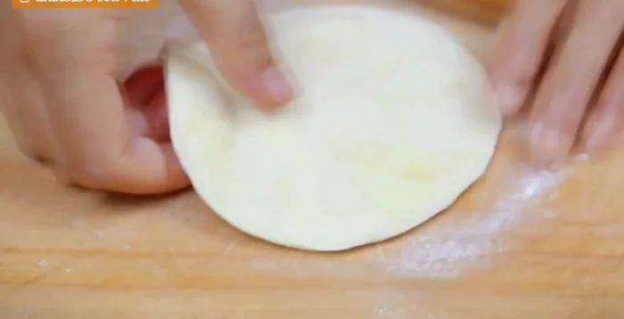 Place a spoonful of mung bean paste onto the center of each wrapper and fold it like a dumpling, sealing the filling. Shape into a round ball and flatten.