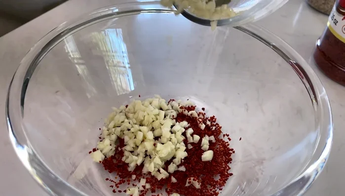 Make the chili oil sauce by heating oil and adding Korean pepper powder, minced garlic, and white sesame seeds. (293.04)