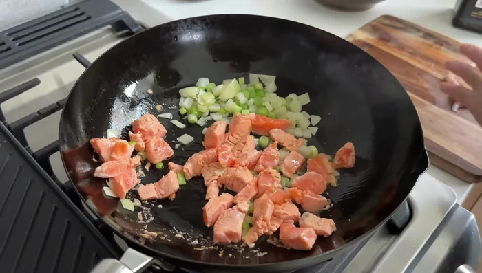 Once salmon changes color, add shrimp and stir-fry everything together. Season with salt and black pepper.