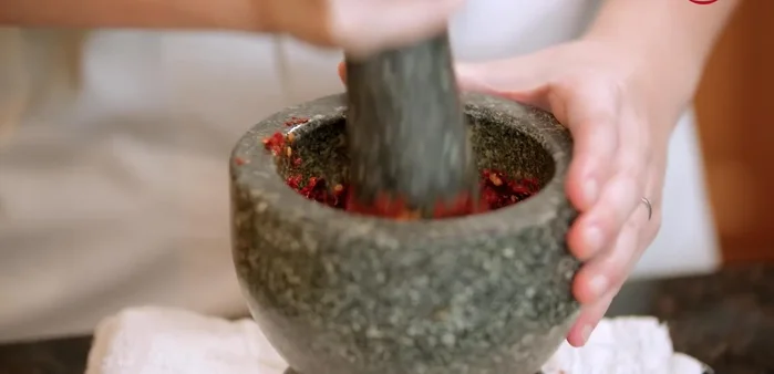 Pound the ingredients in a mortar and pestle, adding salt as a friction agent and adding ingredients one at a time (chilies first, then root, lemongrass, galangal, lime, garlic, and finally shallots).