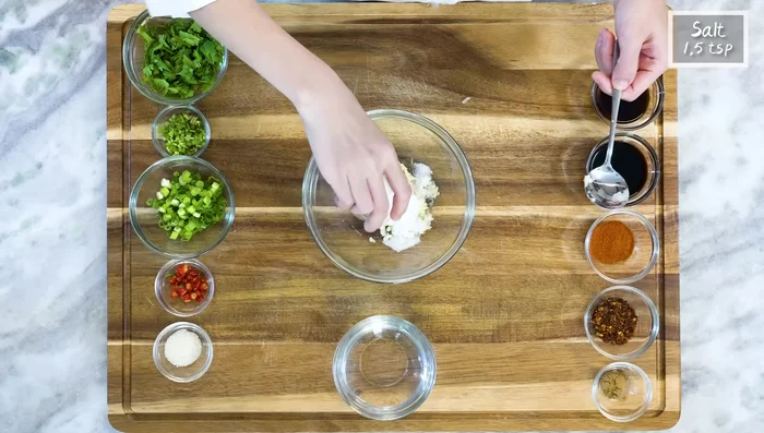 Prepare the dressing: Press garlic, mix with salt, sugar, diced chilies, scallions, cilantro stems, five-spice powder, chili flakes, and paprika. Heat vegetable oil and pour over spices.