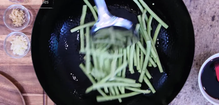 Heat oil in a wok over medium heat. Add yard beans and stir-fry for a few minutes until slightly tender.
