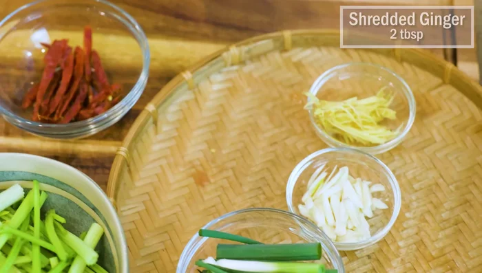 Prepare ginger strips, garlic slices, and cut scallions into stalks.