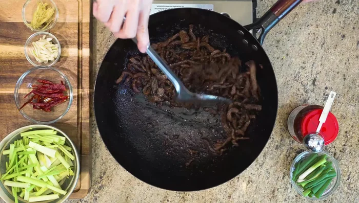 Reduce heat to low. Push beef to the side, add Sichuan Doubanjiang and stir until oil turns bright red.