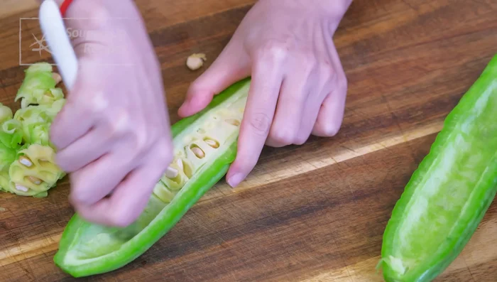 Discard both ends of the bitter melon, cut it in half lengthwise, and remove the white spongy inside using a spoon. Cut into thin slices.