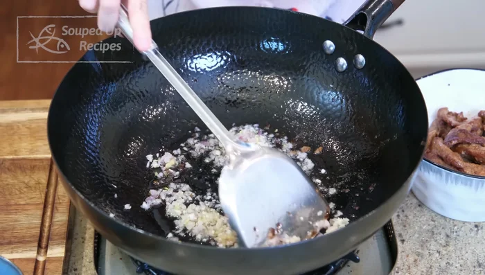 Sauté aromatics: Add minced aromatics to wok and sauté until slightly golden.
