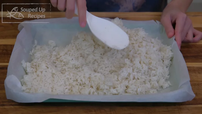 Spread the cooked rice evenly in a parchment paper-lined baking pan, press down firmly. Bake at 200°F (93°C) for 3 1/2 hours, opening the oven door every 30 minutes to release steam.