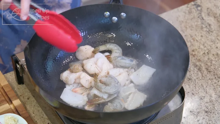 Heat oil in a pan. Sear seafood until golden brown, removing each type as it cooks. Set aside.