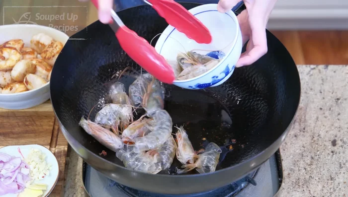 Add more oil to the same pan. Sauté garlic, ginger, and shallot until fragrant. Add shrimp heads and shells, cooking until pink and releasing their oils. Season with soy sauce, oyster sauce, and tomato paste.