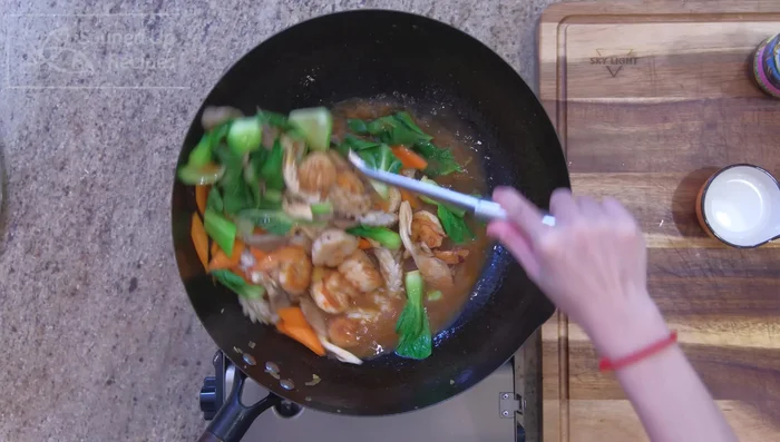 Add carrots, mushrooms, and bok choy to the shrimp stock. Return the cooked seafood to the pot. Stir in a cornstarch slurry (cornstarch mixed with water) to thicken the soup.