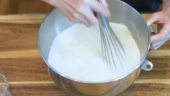 Whisk together flour and salt. Gradually add room temperature water, mixing until a dough forms. Use less water if possible.