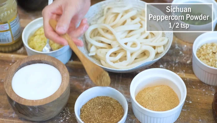 Prepare the sauce: Combine sugar, Sichuan peppercorn powder, roasted soybean powder, minced garlic, sesame butter, seasoned sweet soy sauce, red chili oil, crushed peanuts, and diced scallions. Mix well.