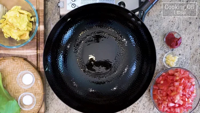 Add another tablespoon of oil to the wok, add diced tomatoes, minced garlic, and tomato paste. Stir until paste dissolves.