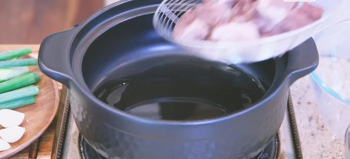 Preheat the clay pot. Add cooking oil, then add the blanched beef, garlic, ginger, and scallions. Stir until fragrant.