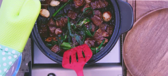 Pour in the seasoning mixture and stir for 1-2 minutes. Add 4 cups of reserved broth and bring to a boil. Reduce heat to low and simmer for 2 hours, adding hot water as needed.
