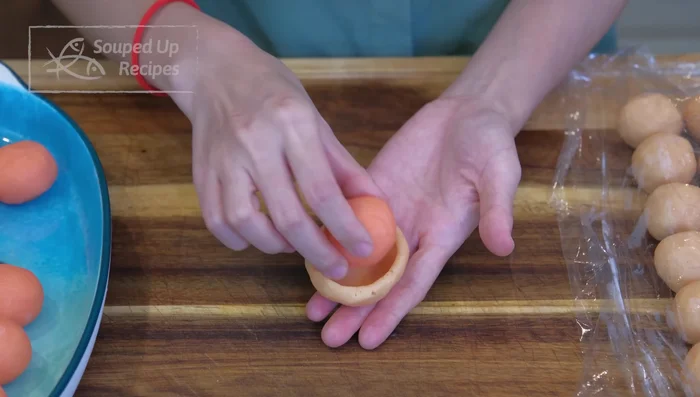 Wrap each custard filling with a dough ball, using a mooncake presser (or shaping by hand).