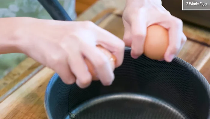 Crack two eggs into a non-stick pot. Remove any shell fragments.