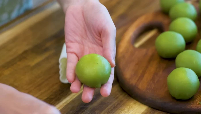 Dust the mooncake balls with cooked glutinous rice flour, place them in a mooncake mold, and press to shape.